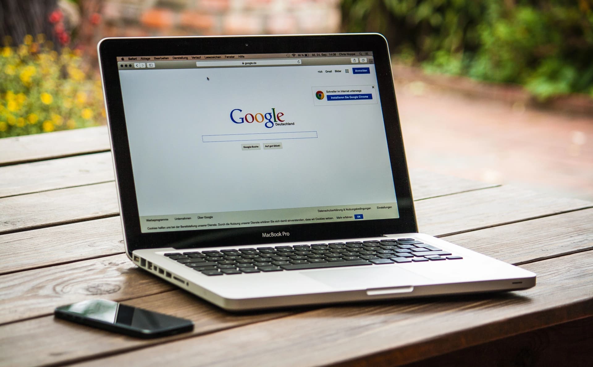 Laptop mit geöffneter Google-Suche auf einem Holztisch im Freien